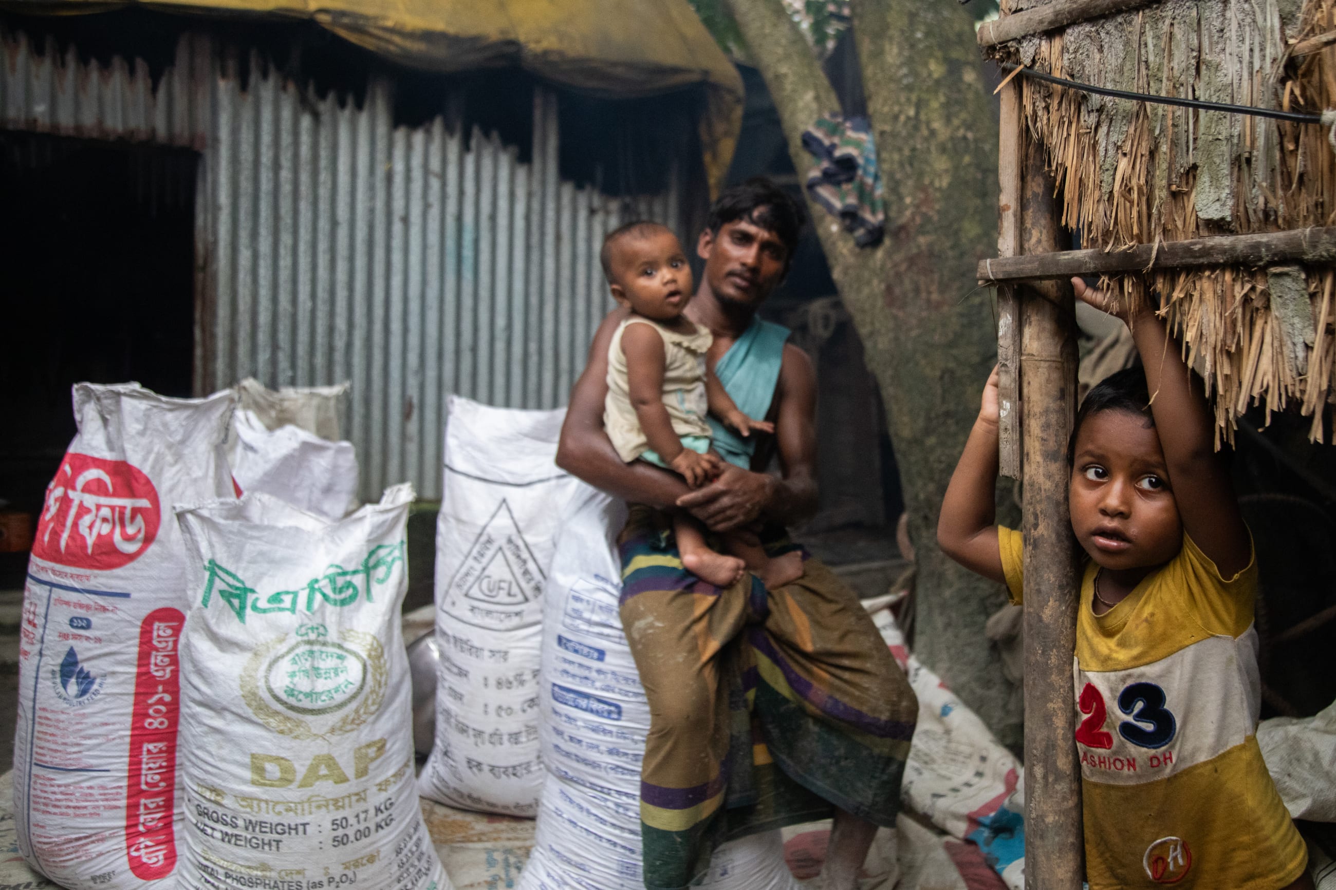Subrata Das (right) waits as his mother, Bobita Rani Das, cooks fish , in Kishoreganj, Bangladesh, on May 21, 2026.