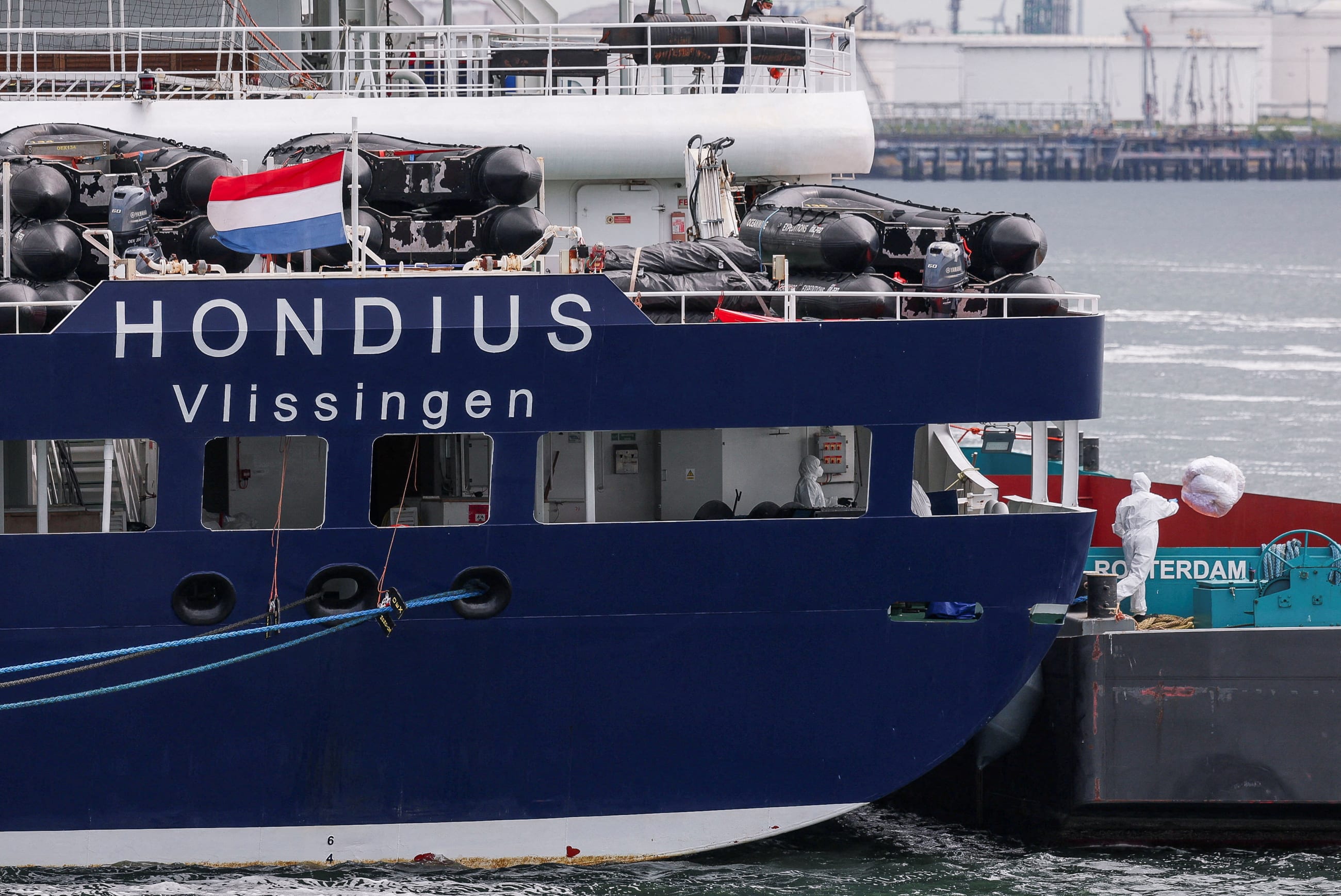 A person wearing protective equipment throws a bag with waste next to the cruise ship MV Hondius, which was affected by a hantavirus outbreak, after it arrived at the Port of Rotterdam, in Rotterdam, Netherlands, on May 18, 2026.