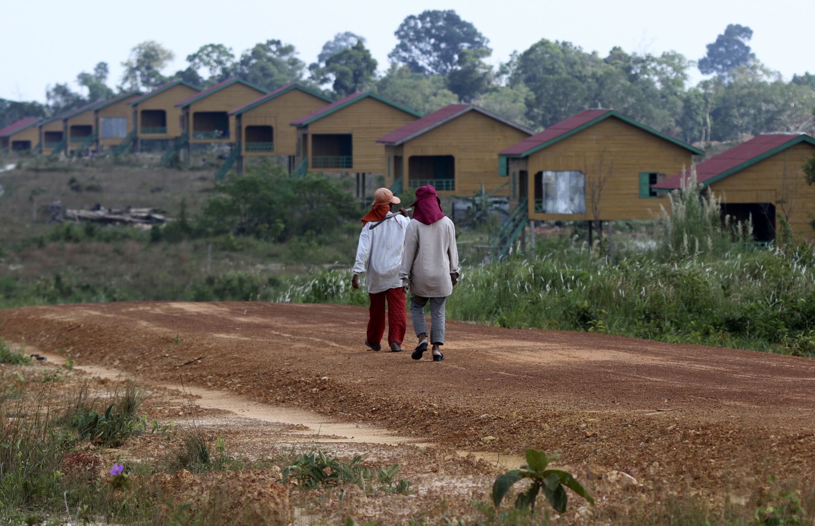 Women walk past houses, in Koh Kong province, Cambodia, on February 20, 2012.