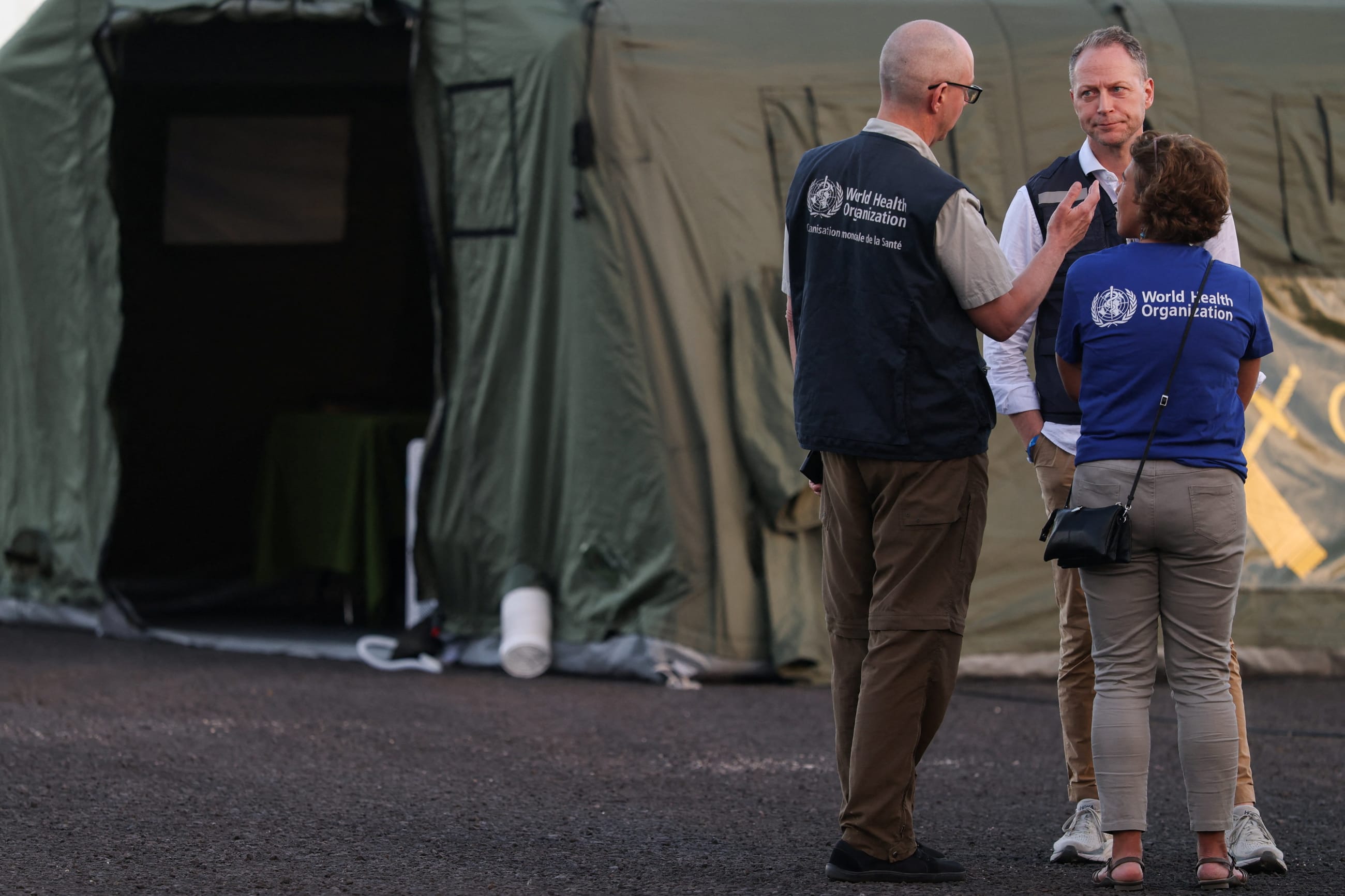 Members of the World Health Organization speak as they gather near a civil guard tent installed at the port of Granadilla de Abona, in Tenerife, Spain, on May 9, 2026.