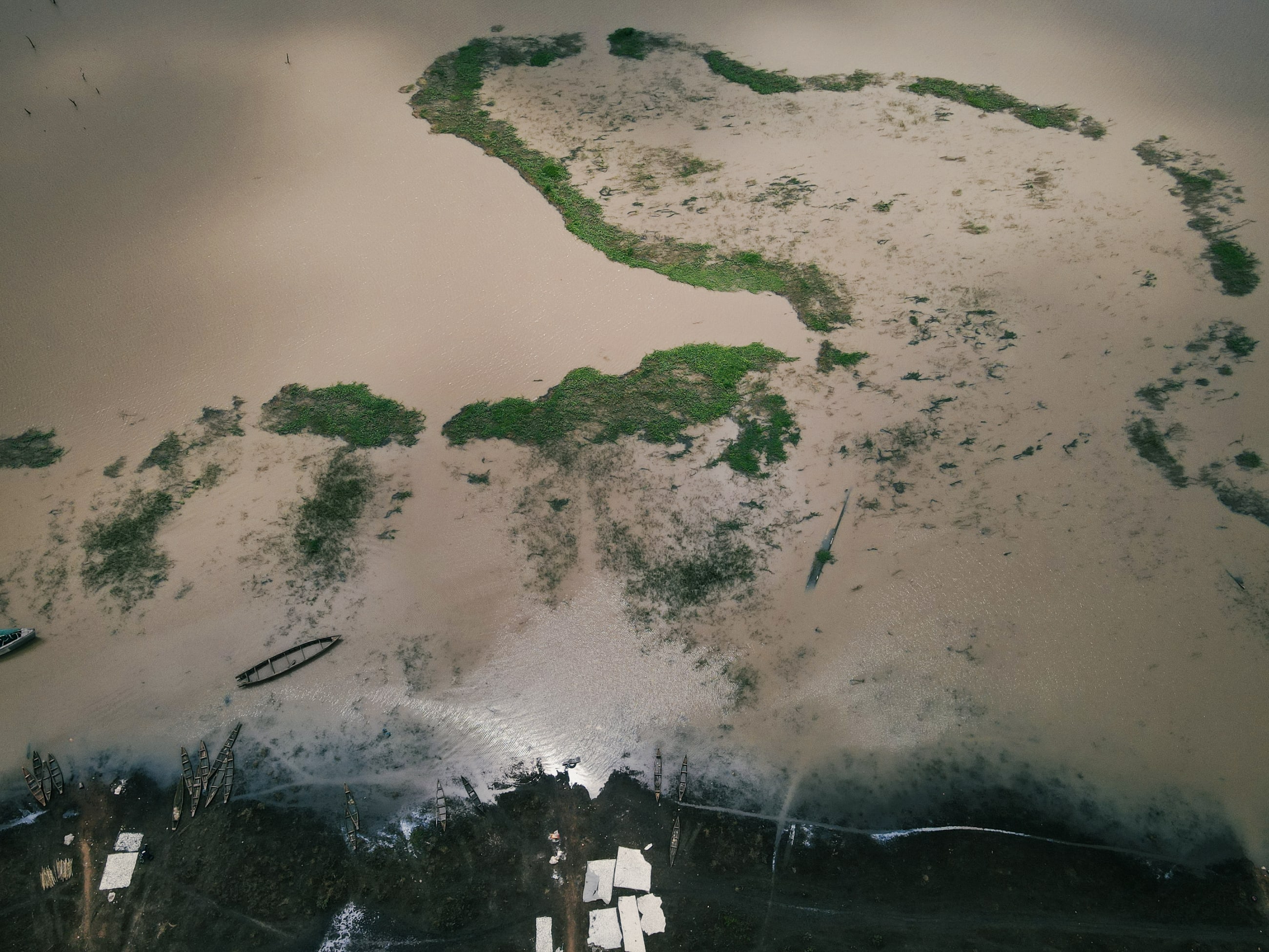 A river access site is seen along the south shore of the Oyan River, which serves as a fishing boat dock and cassava root processing site, on July 2025.