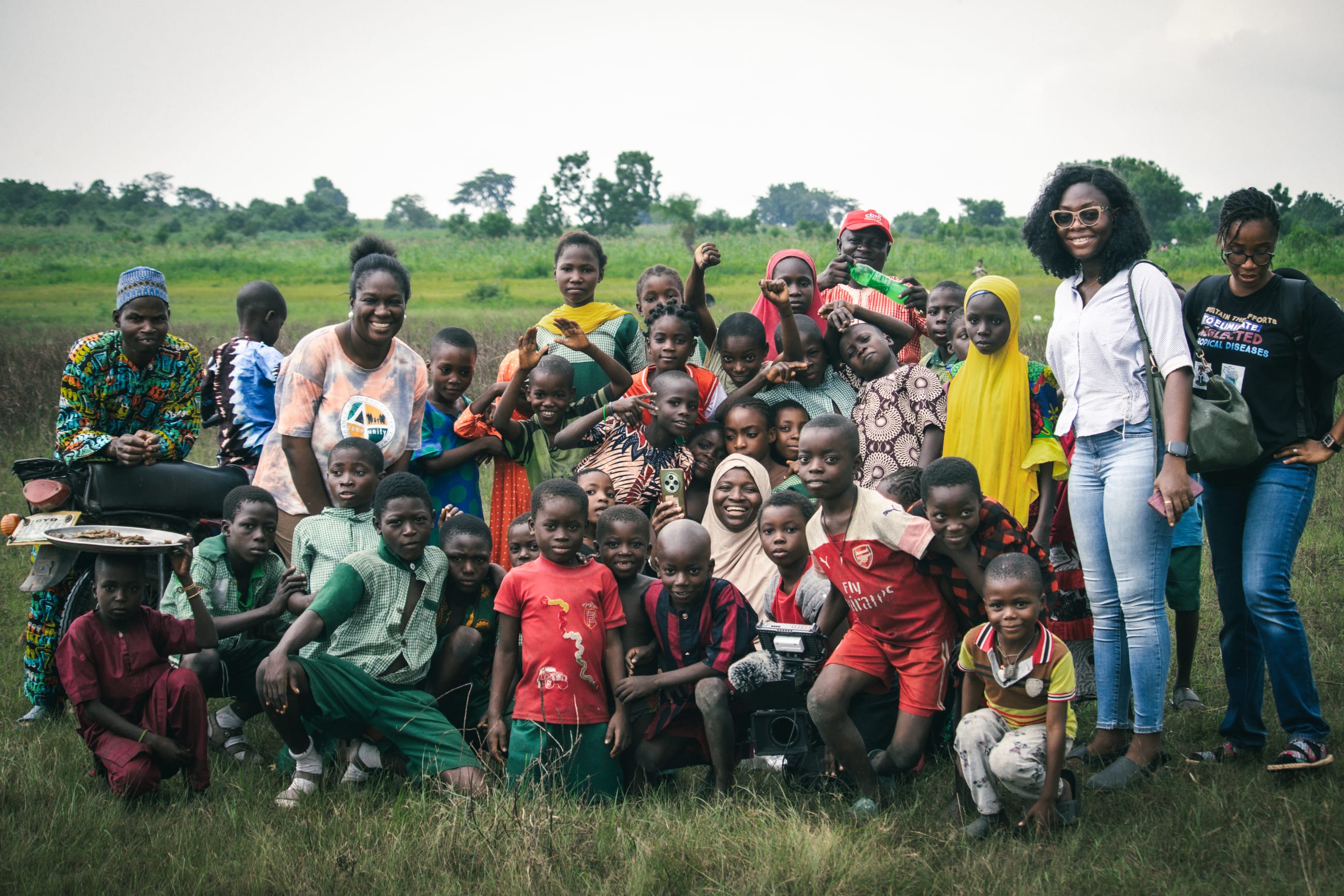 Neglected Tropical Disease Office leadership, doctors, and researchers pose with residents and schoolchildren at a survey site, on July 2025.