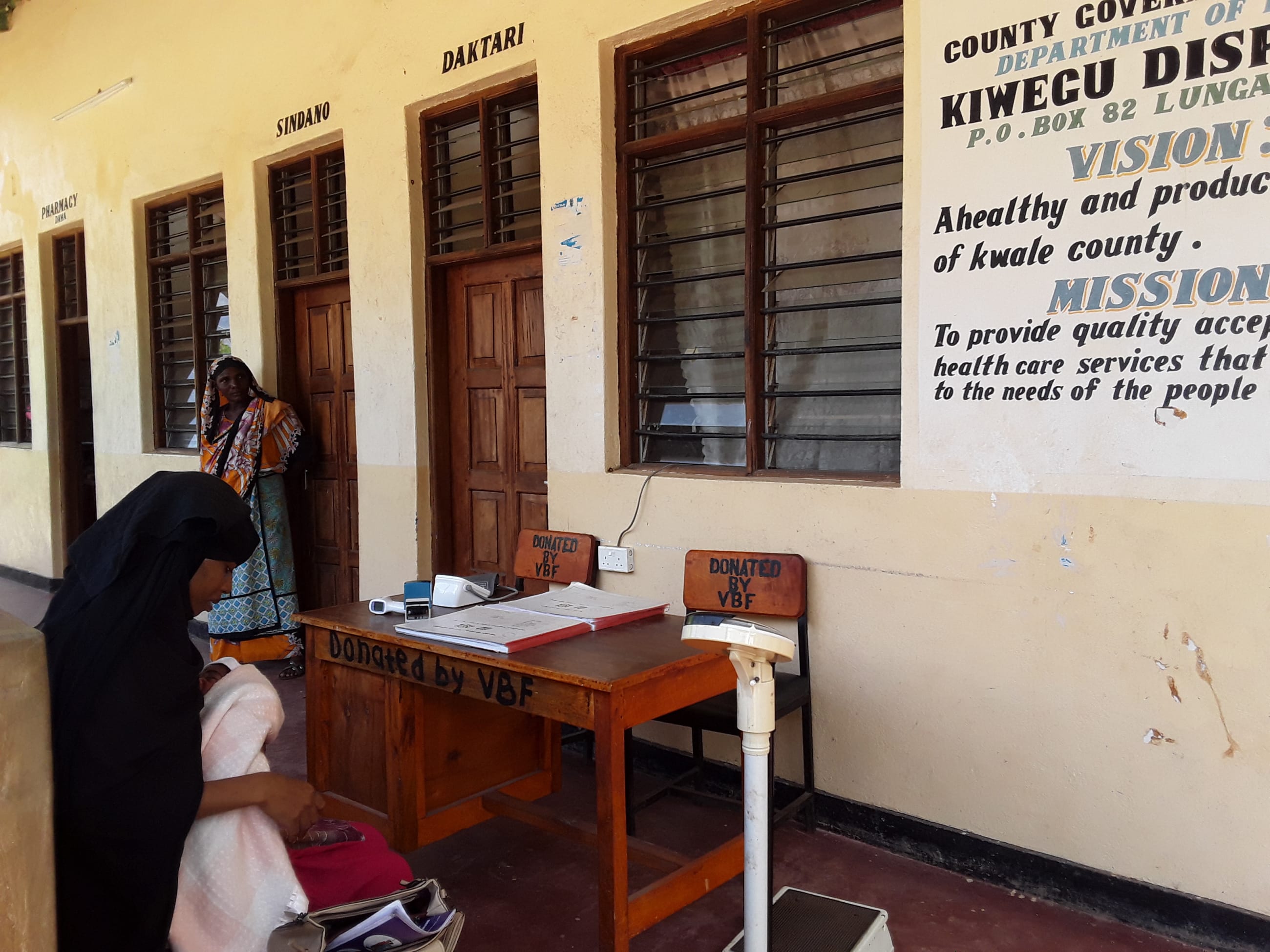) Fatuma Kassim is waiting for services with her newborn baby, born at Kiwegu dispensary. The clinic has ongoing partnerships with the Vanga Blue Forest project, including furniture donated by the project.