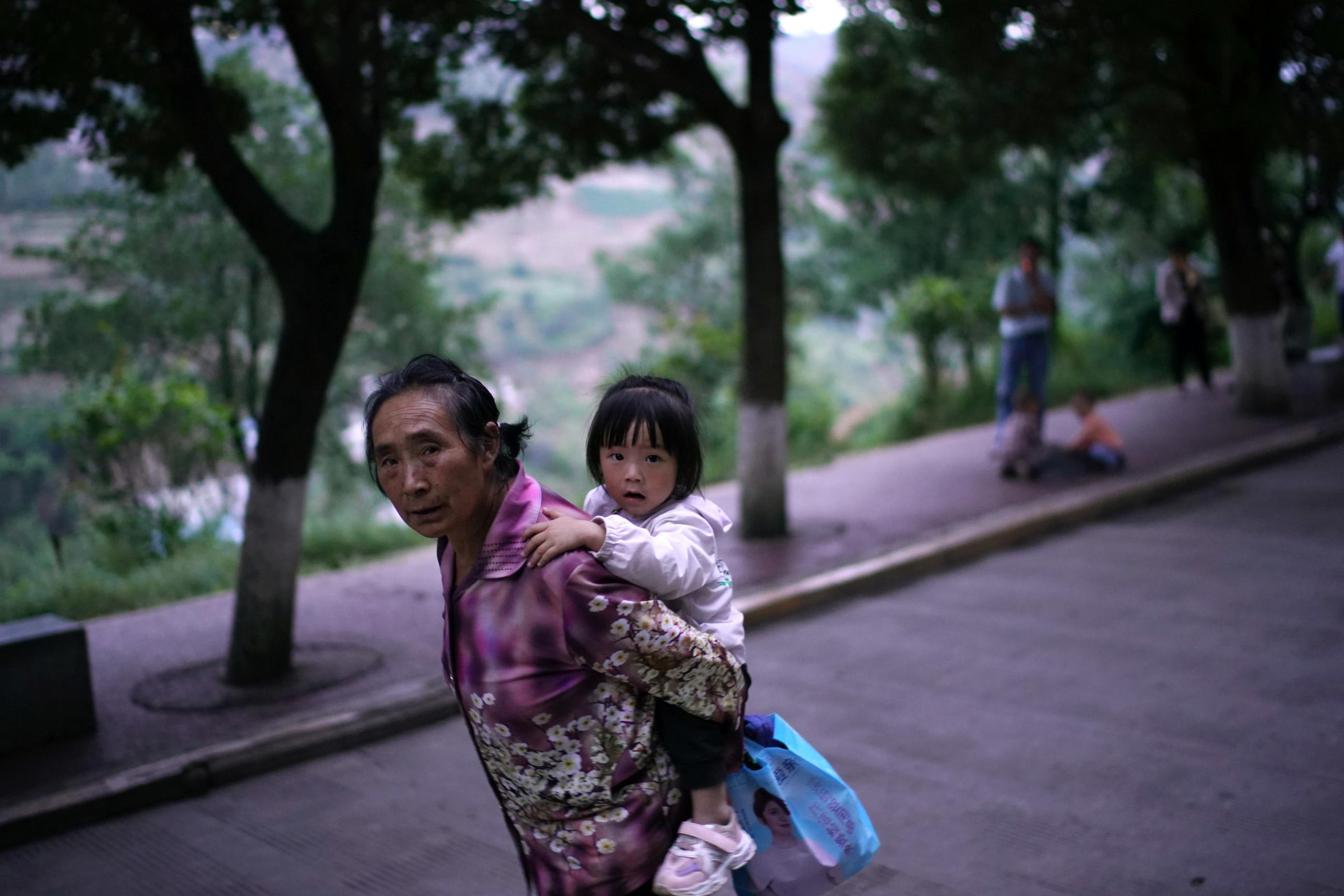 An elderly woman carrying a young girl on her back walks on a street in Ganluo county, Liangshan Yi Autonomous Prefecture, Sichuan province, China on September 9, 2020.