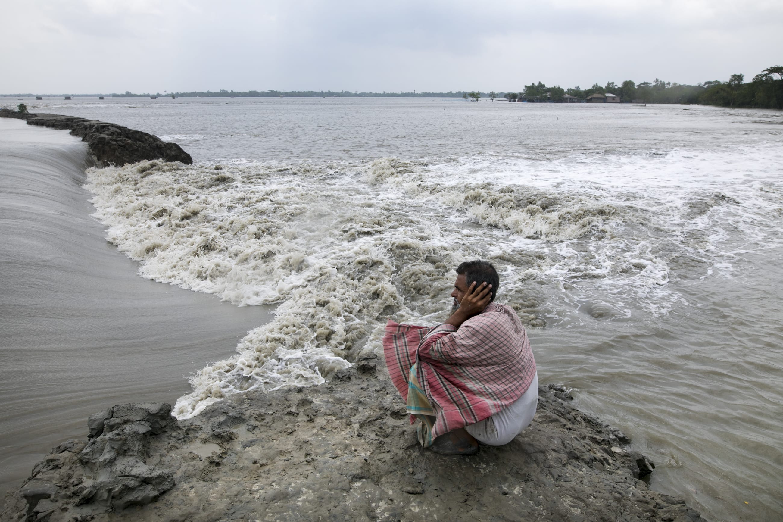 A man, Sobhan Mia, sits beside his land in coastal Bangladesh, flooded with saltwater after an embankment collapsed during Tropical Cyclone Yaas in 2021. Photo taken on May 27, 2021, in Koyra subdistrict, Khulna district.
