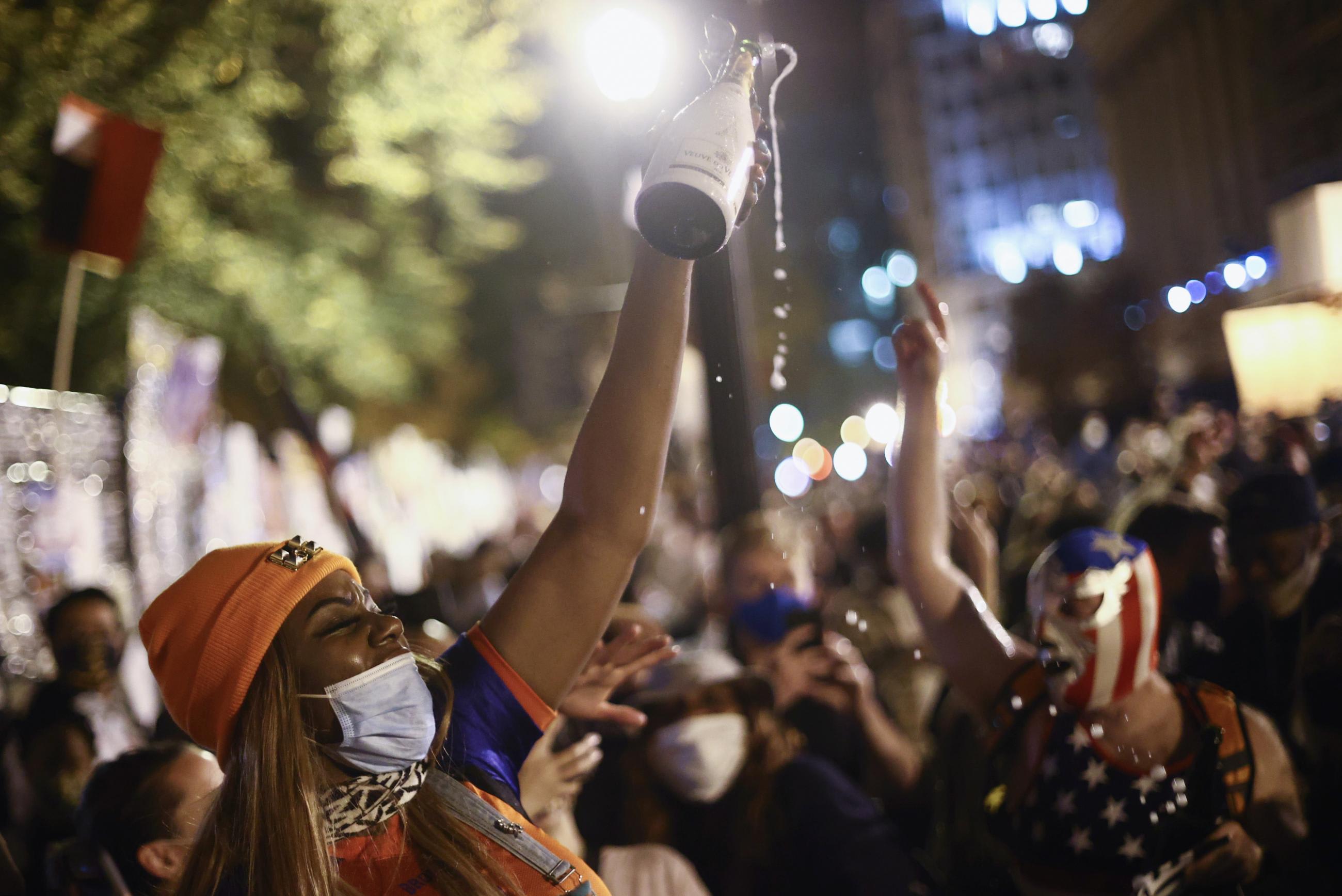 People open a bottle of champagne after news media declared Democratic candidate Joe Biden to be the winner of the 2020 U.S. presidential election, at BLM Plaza in Washington, DC, U.S., November 7, 2020.