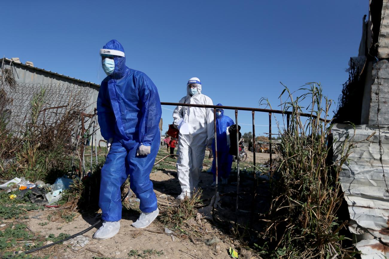 Palestinian medical workers walk as they arrive to collect swab samples from people to be tested for the coronavirus disease, in the Gaza Strip on January 14, 2021.
