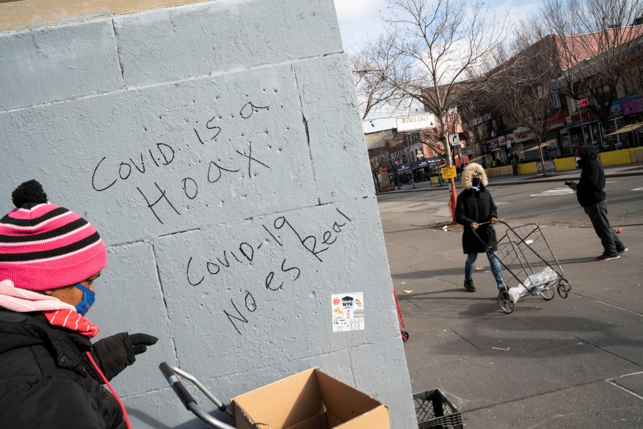 People wait in line next to graffiti the reads "Covid is a Hoax" at The Bronx Temple SDA Community Services Pantry amid the coronavirus disease (COVID-19) pandemic in the Bronx borough of New York City, New York, U.S., January 6, 2021.