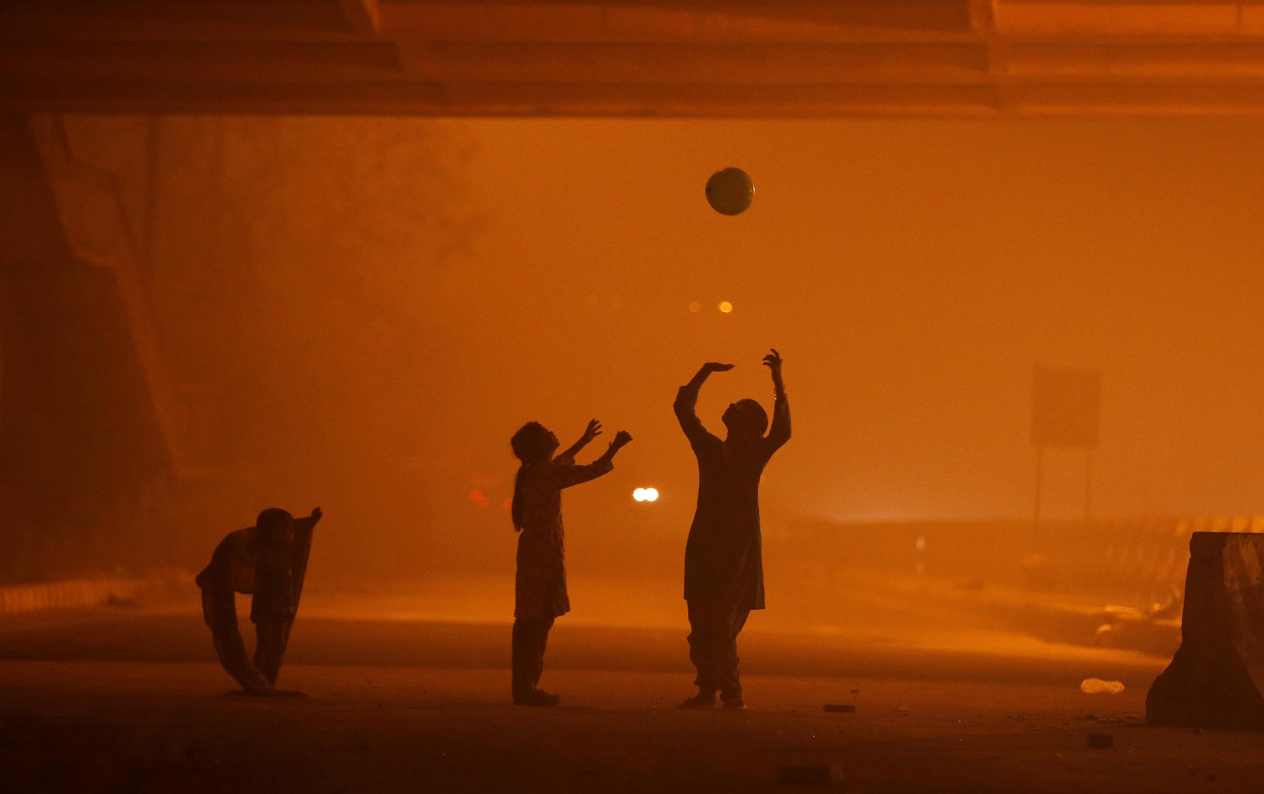 Girls play with a balloon under a flyover amidst the heavy smog in New Delhi, India, November 6, 2016.