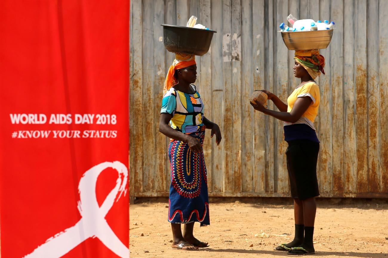 Women stand near a banner during an HIV/AIDS awareness campaign on the occasion of World AIDS Day at the Kuchingoro IDPs camp in Abuja, Nigeria, on December 1, 2018.