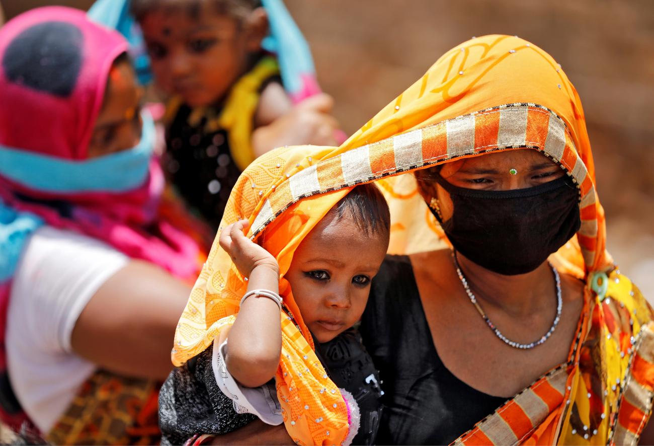 A mother drapes an orange sari over her baby to protect him from the heat in Ahmedabad, India, May 20, 2020.