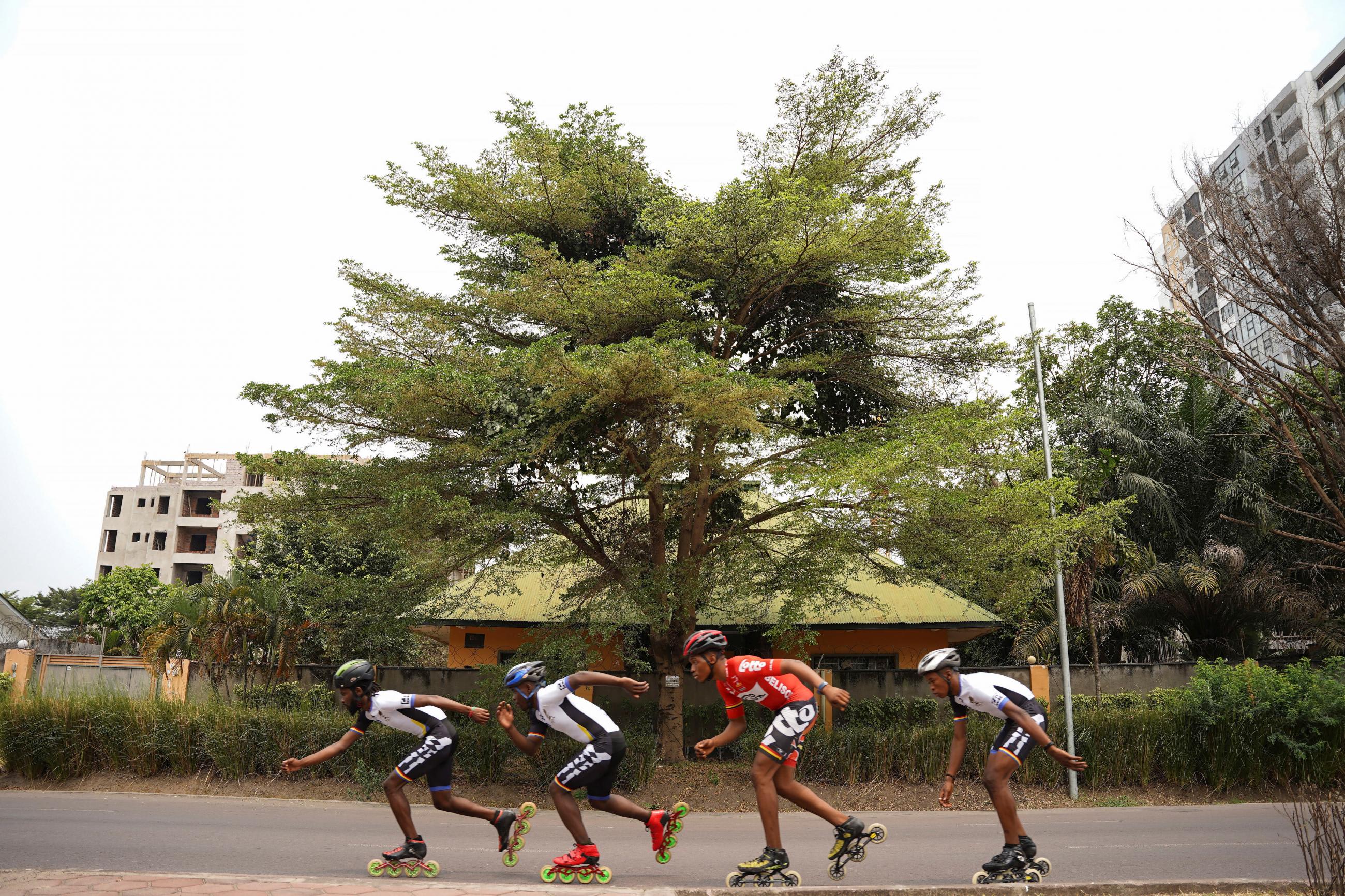 Serge Makolo leads his team of four speed skaters past a large green treeduring a training in Kinshasa, Democratic Republic of Congo, on September 16, 2021.