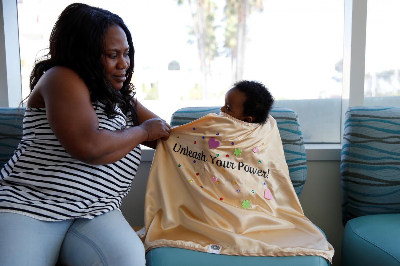 Four-month-old cancer patient Audrey has her mother Bertha place a cape on her at Rady's Children Hospital after decorating golden capes that say "Unleash Your Power" to wear as superheroes as part of Childhood Cancer Month in San Diego, California, U.S., September 4, 2019.