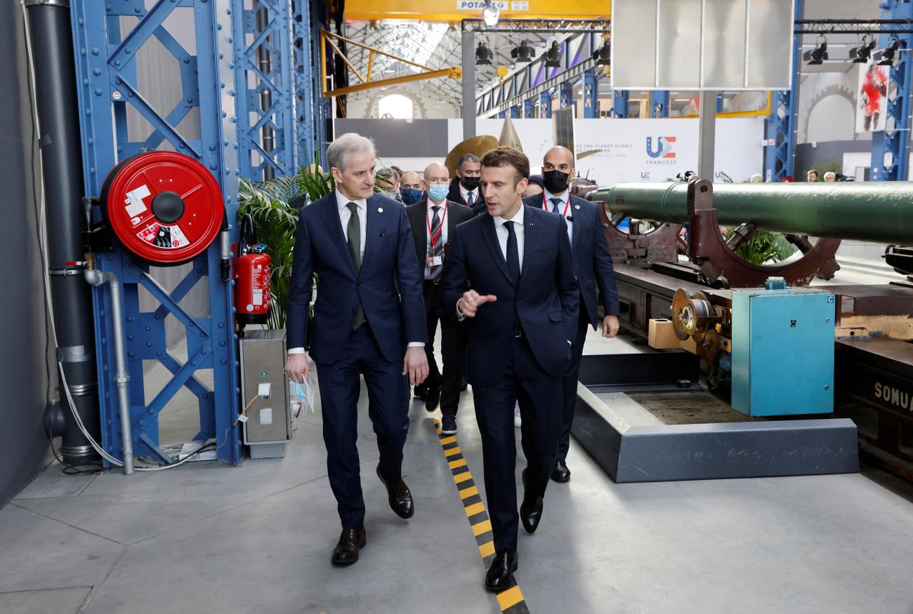 Norway's Prime Minister Jonas Gahr Store (L) talks to France's President Emmanuel Macron (R) in an exposition space at the One Ocean Summit.