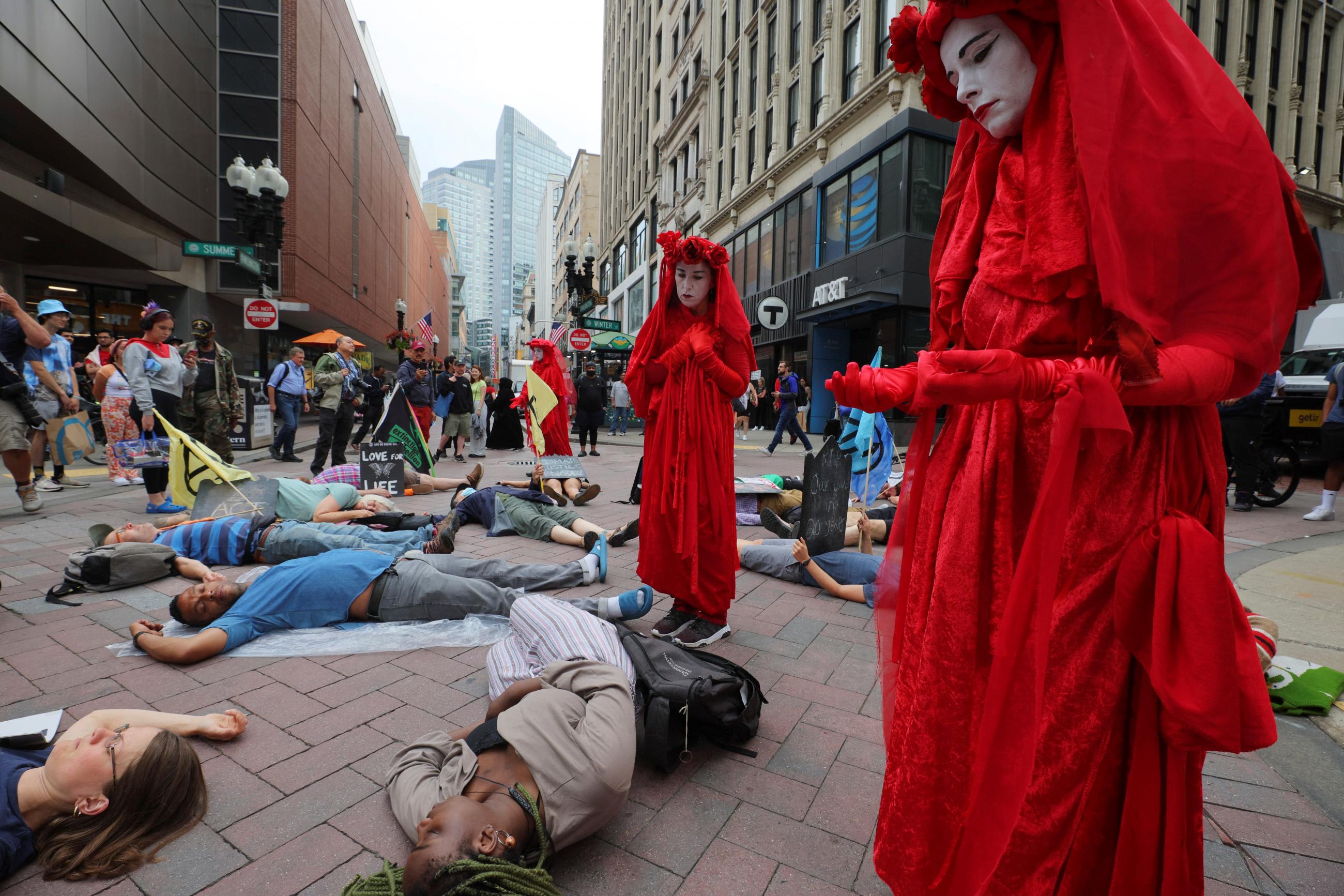 Activists dressed in red cloaks, inspired by the costume design from a "handmaid's tale" demonstrate in the street in front of protestors, who are laying down on pavement, on the streets of Boston, Massachusetts.
