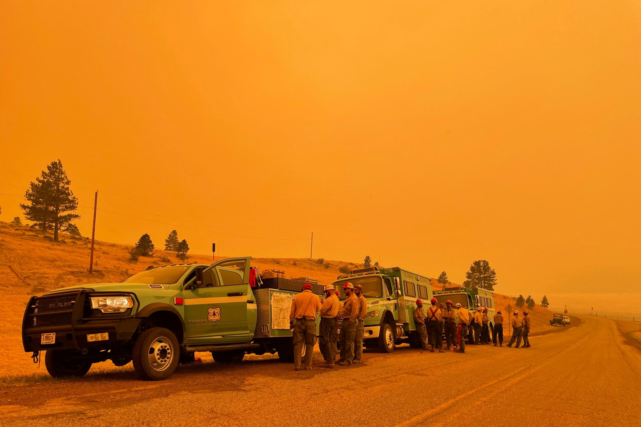 Smoke casts an orange haze as firefighters hold a briefing in the Black Lake, New Mexico area north of the Calf Canyon Hermits Peak wildfire, which was declared a public health emergency, in the United States on May 11, 2022.
