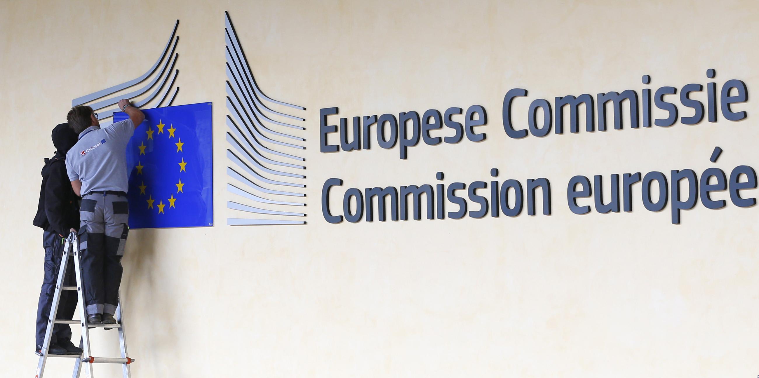 Workers adjust and clean the logo of the European Commission at the entrance of the Berlaymont building, the EC headquarters, in Brussels September 12, 2013.