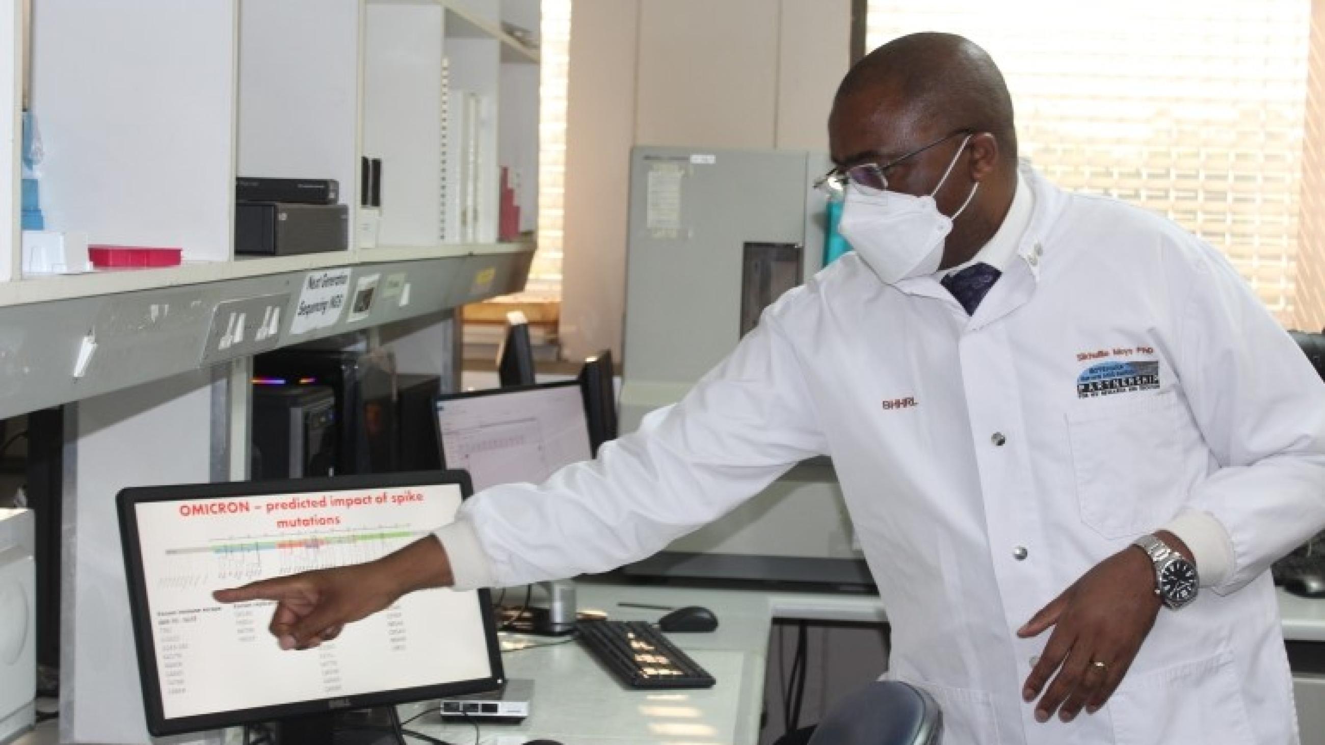 Dr. Sikhulile Moyo points to a computer, describes his team's findings during a visit by President of Botswana, Mokgweetsi Masisi, December 2, 2021.
