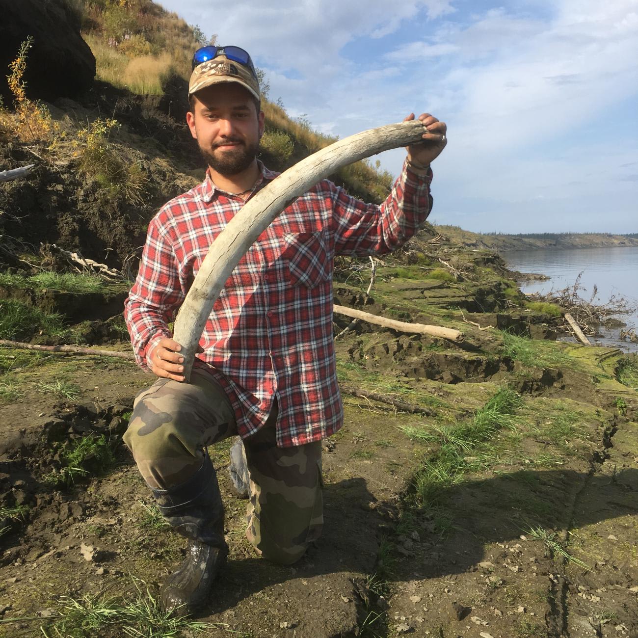 Dr. Eugène Christo-Foroux proudly presenting the mammoth tusk he just found on the bank of the Kolyma river at Duvanny Yar, in August 2019.
