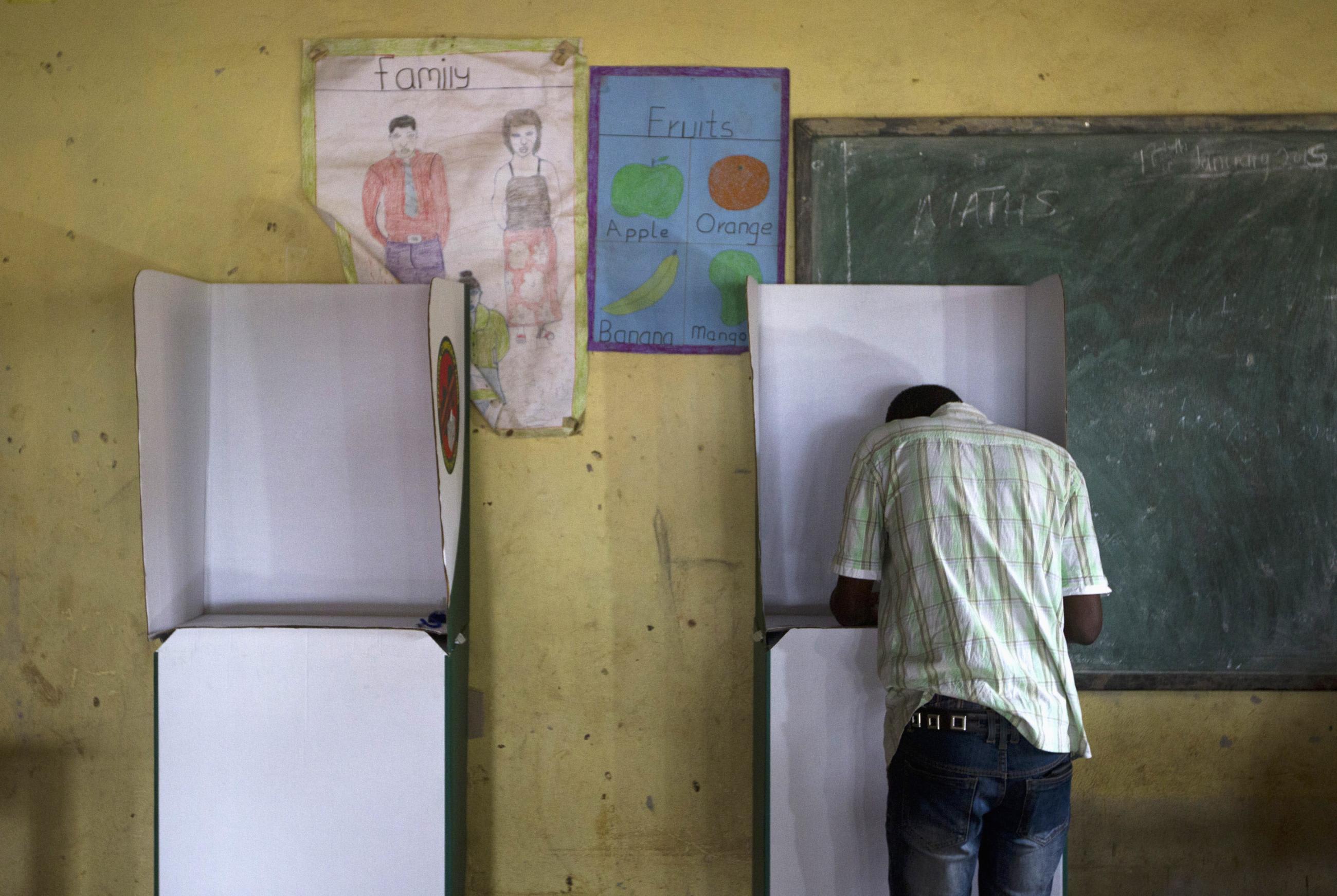 A voter marks his ballot at a voting station in John Howard township in Lusaka on January 20, 2015.