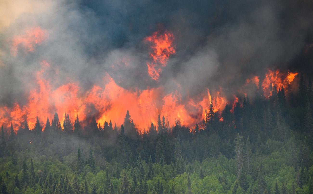 Flames reach upward along the edge of a wildfire as seen from a Canadian Forces helicopter surveying the area near Mistissini, Quebec, Canada, on June 12, 2023.