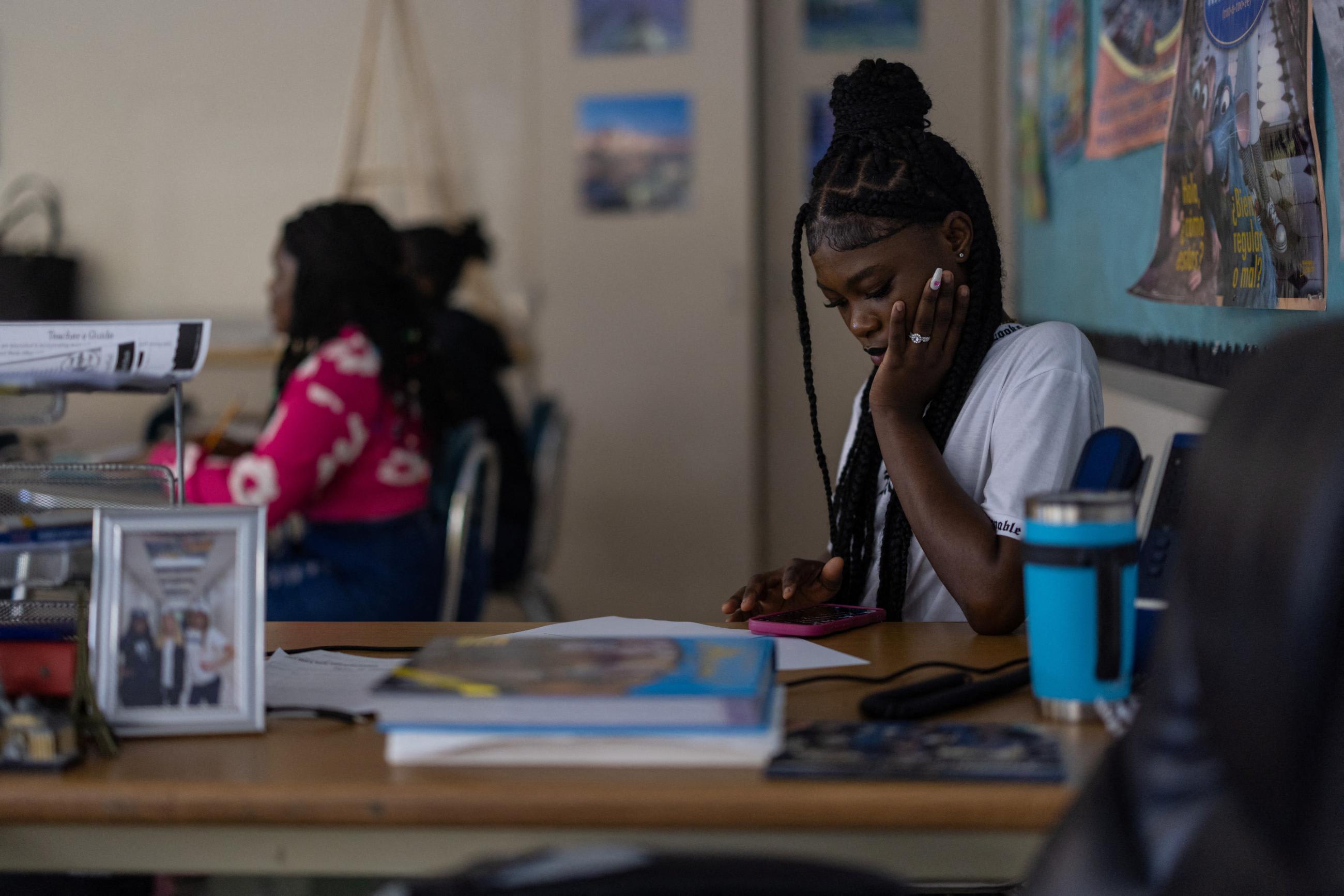 Julnise Telorge, a high school senior, looks at her phone during class at her local high school.