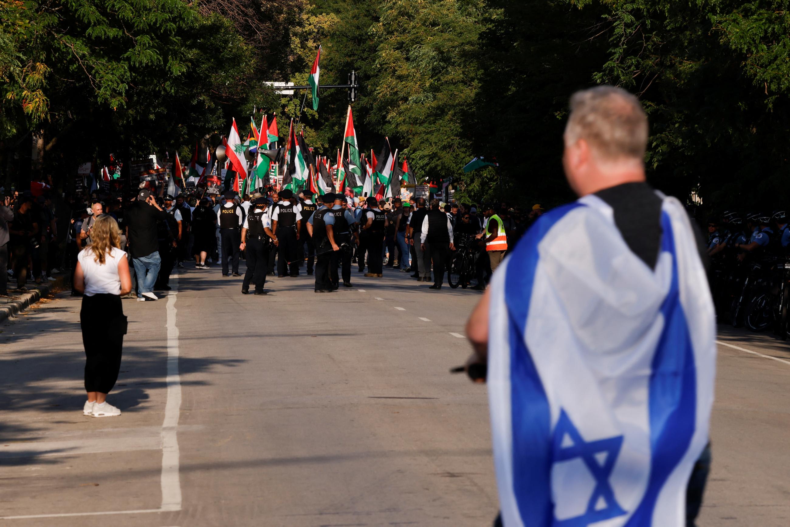 A person covers themselves with an Israeli flag during a protest in support of Palestinians in Gaza, on the sidelines of the Democratic National Convention in Chicago, August 21, 2024.