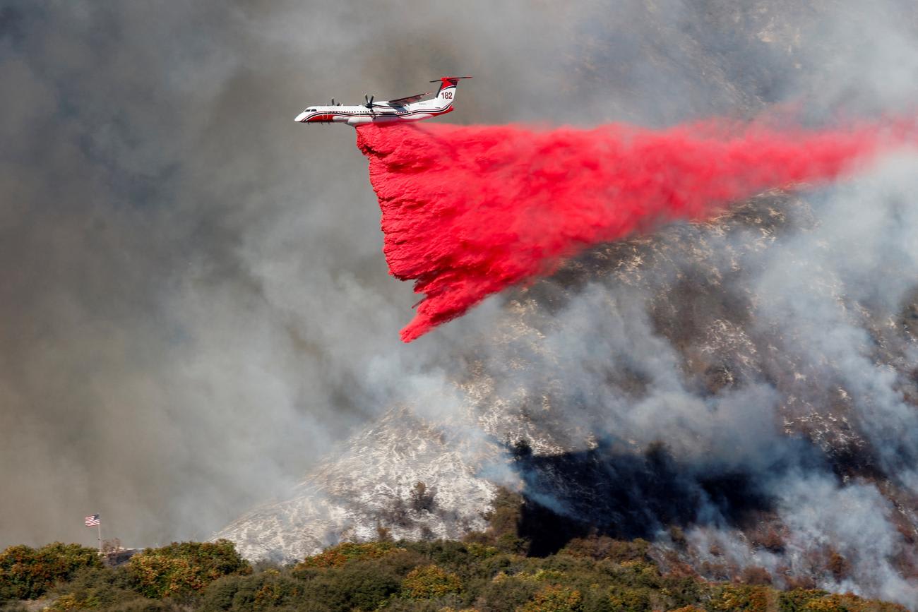 A plane makes a drop as smoke billows from the Palisades Fire at the Mandeville Canyon, in Los Angeles, California, on January 11, 2025.