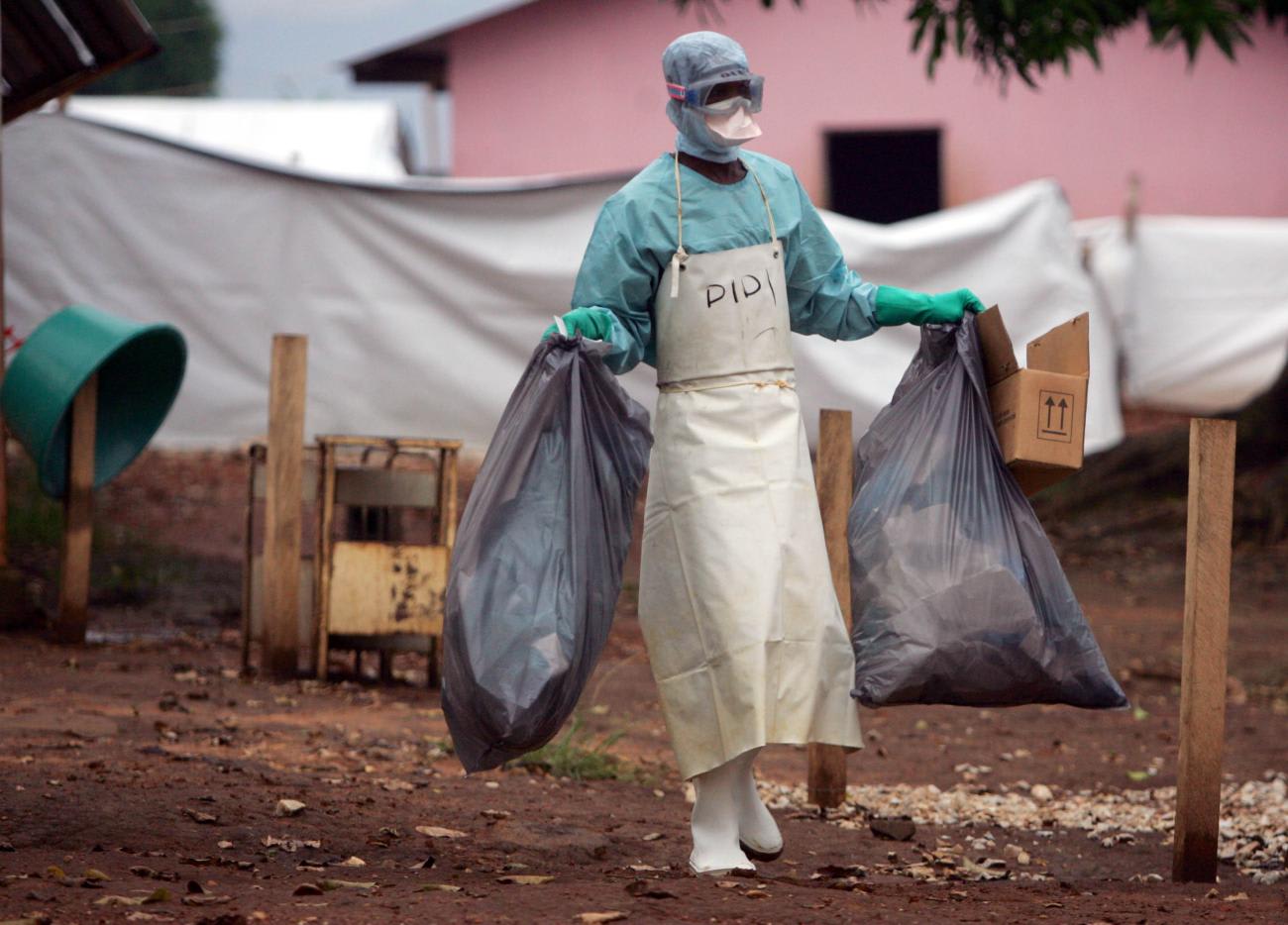 A health worker in protective clothing carries waste for disposal outside the Marburg isolation ward