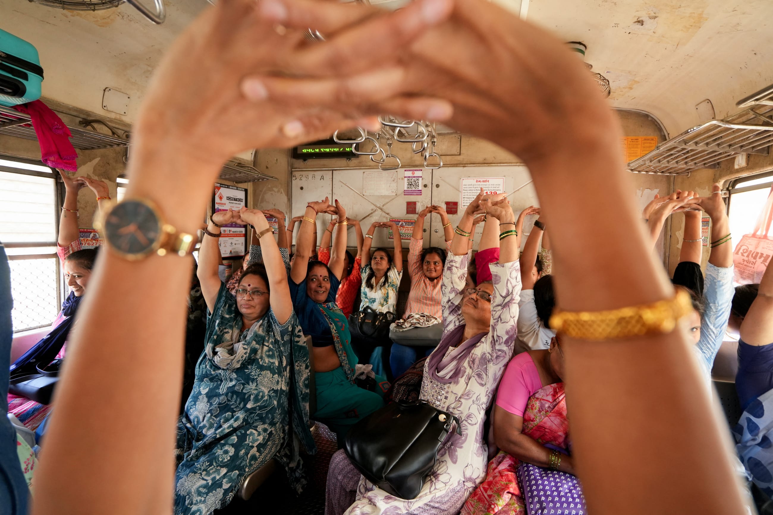 Women practice yoga in a local train on International Women's Day in Mumbai, India, on March 8, 2025.