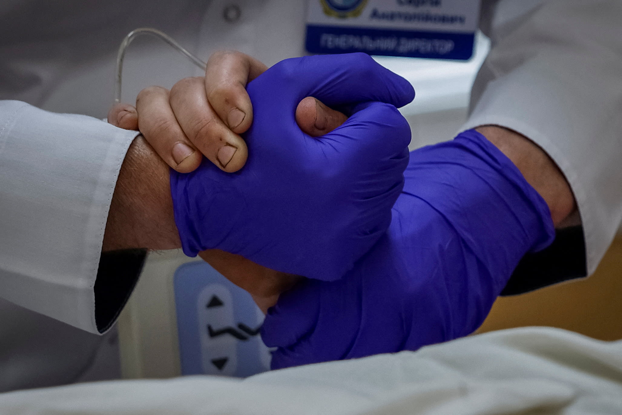 Serhii Ryzhenko, general manager of the Mechnykov Hospital, holds the hand of a patient, in Dnipro, Ukraine, on May 14, 2025.