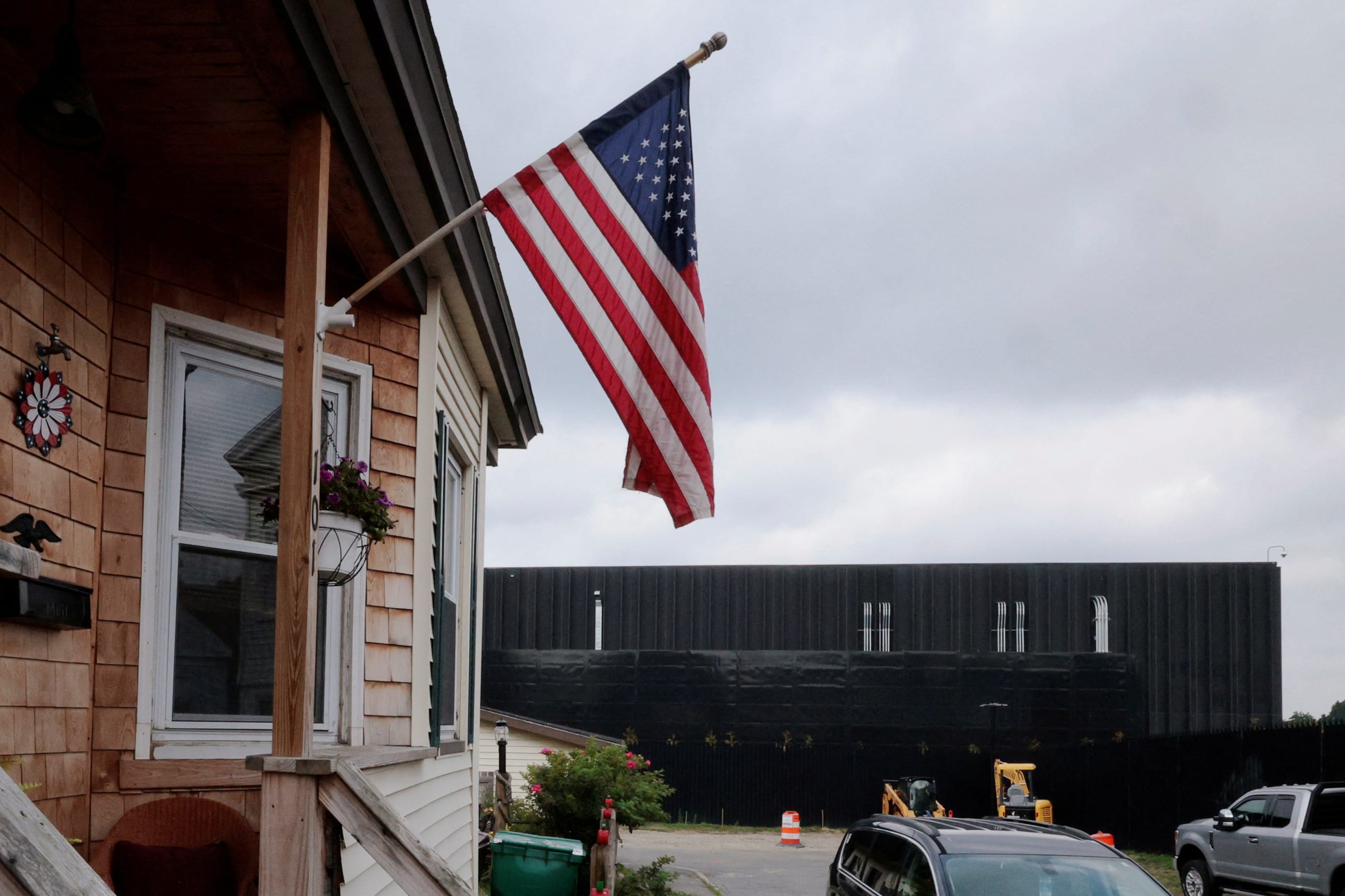 A U.S. flag flutters from a home beside the Markley Group data center, in a residential neighborhood, in Lowell, Massachusetts, on July 28, 2026.