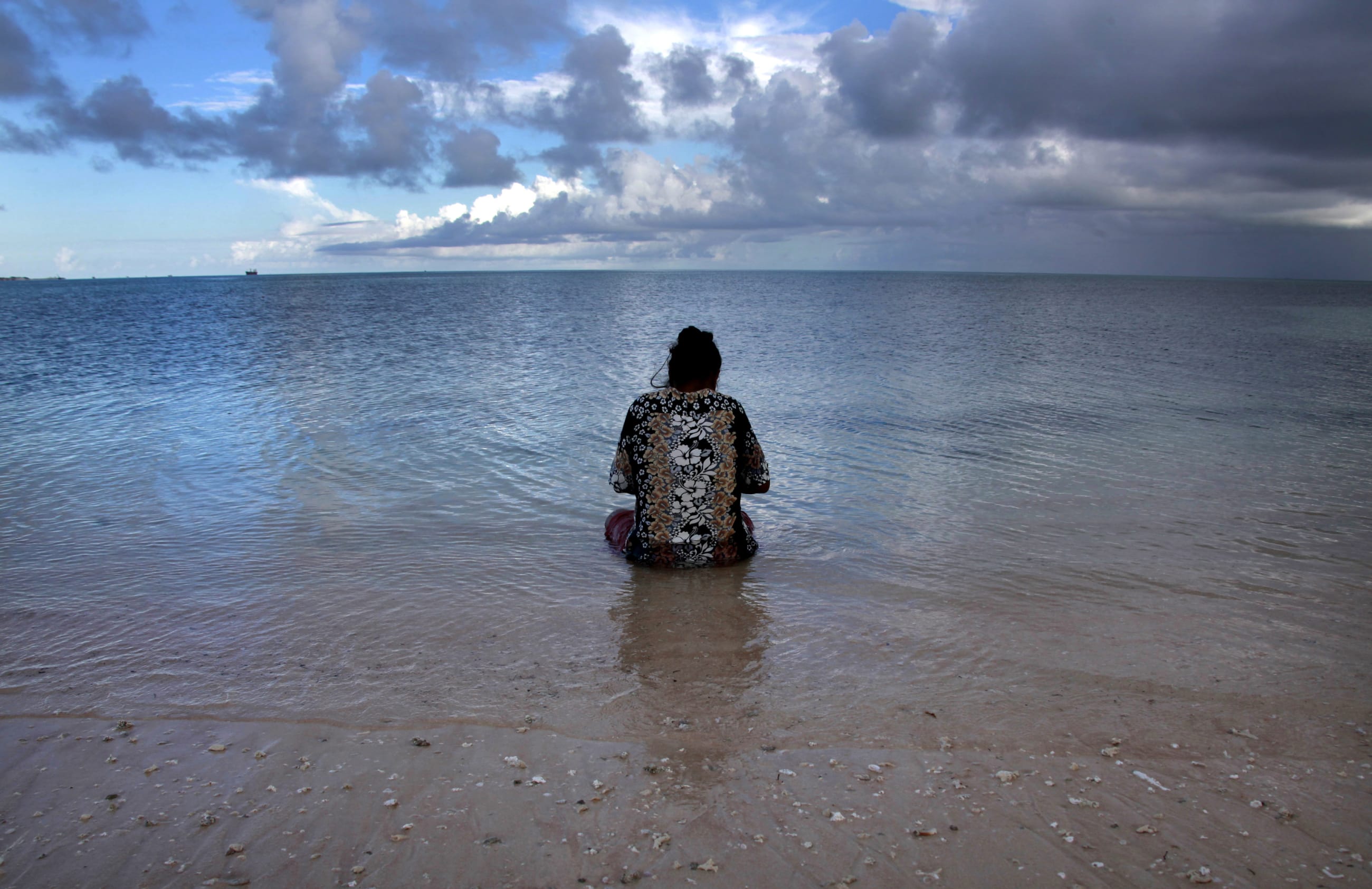 Binata Pinata scales a fish her husband caught, as she sits in the sea just off Bikeman islet, located off South Tarawa, in the central Pacific island nation of Kiribati, on May 25, 2013.