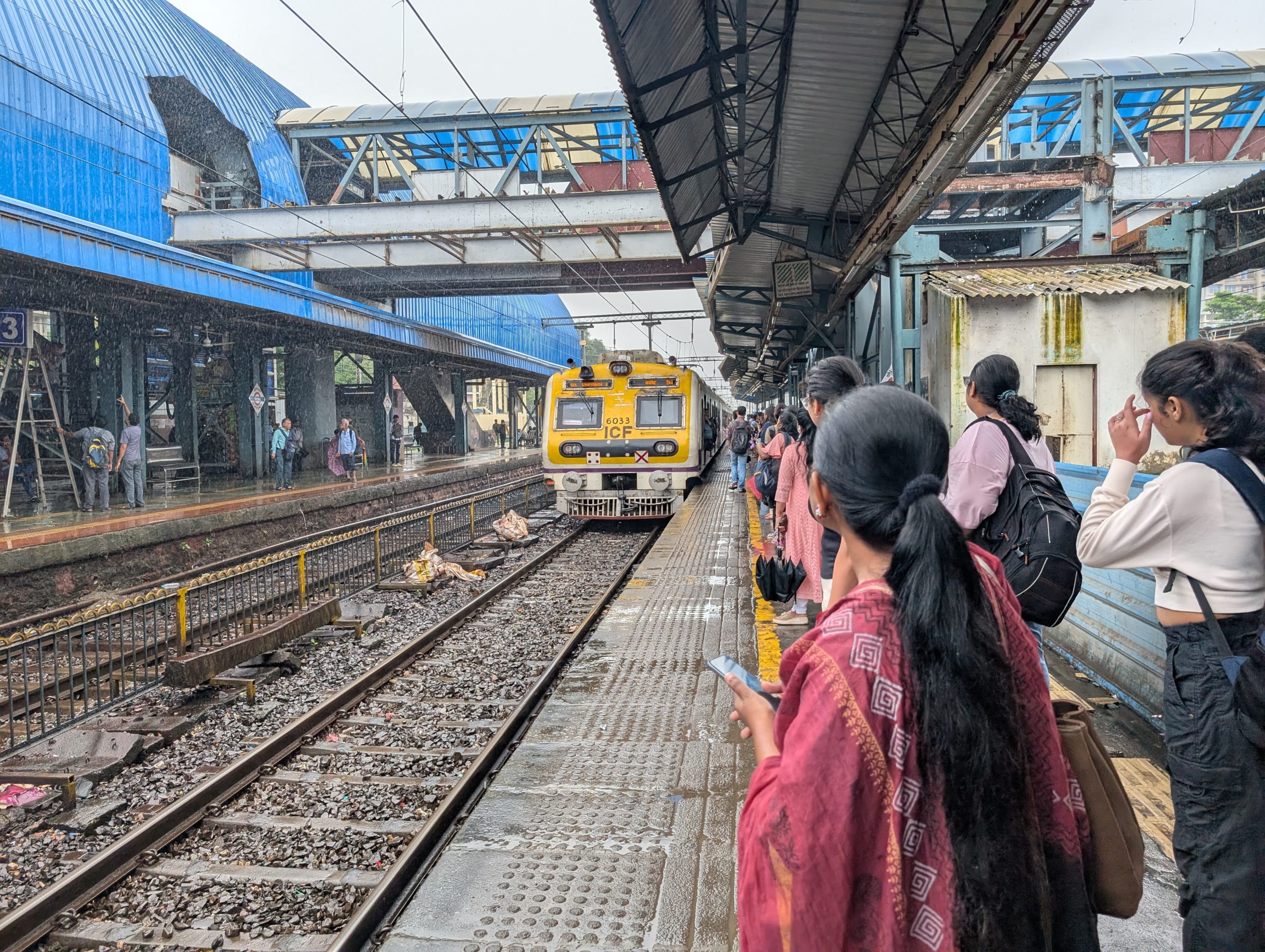 Commuters wait for a train at Goregaon railway station in suburban Mumbai on August 7, 2025.