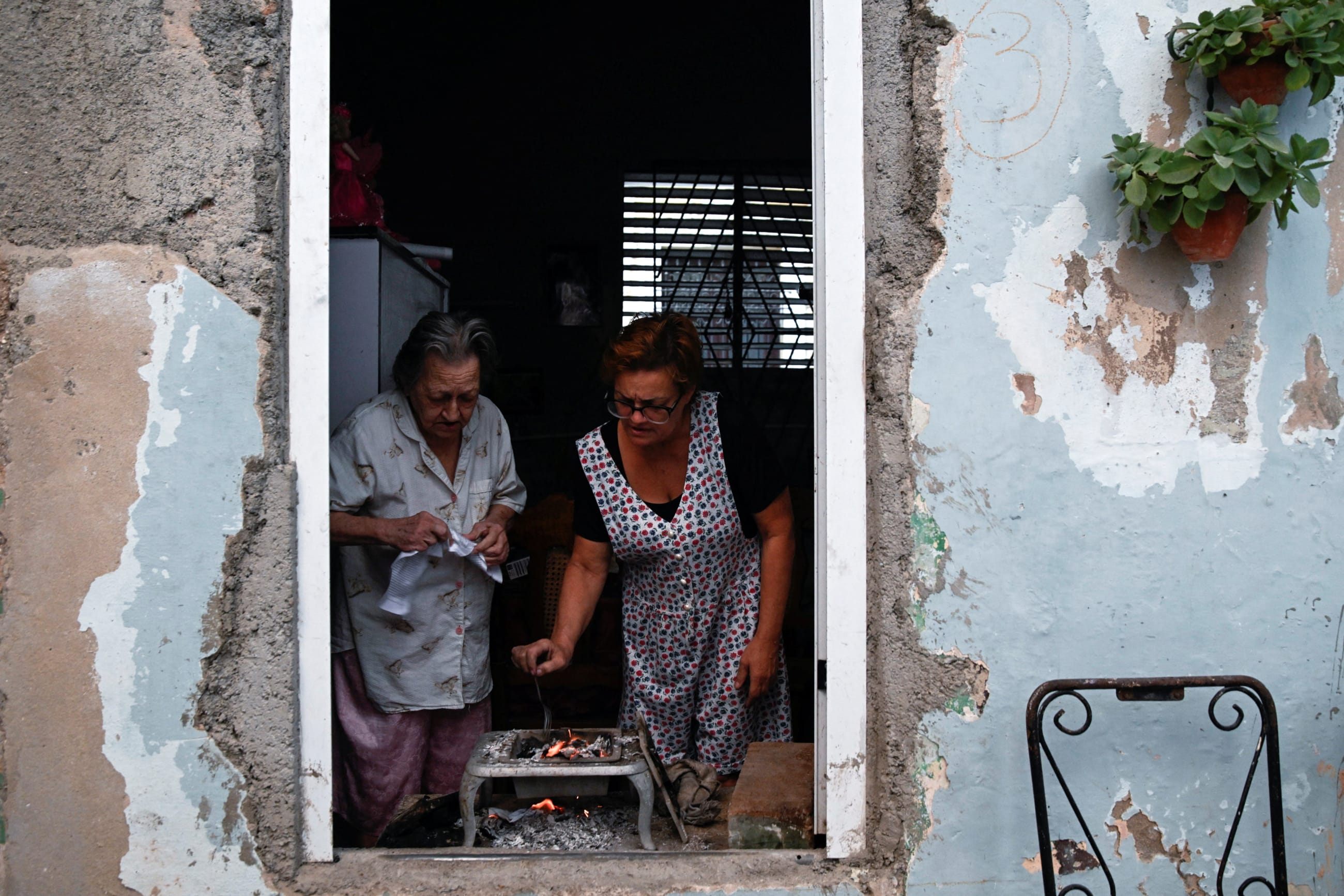 Two women cook dinner after Cuba's national electric grid collapsed for the second time in a week, amid the U.S.-imposed oil blockade, in Havana, Cuba, on March 21, 2026.
