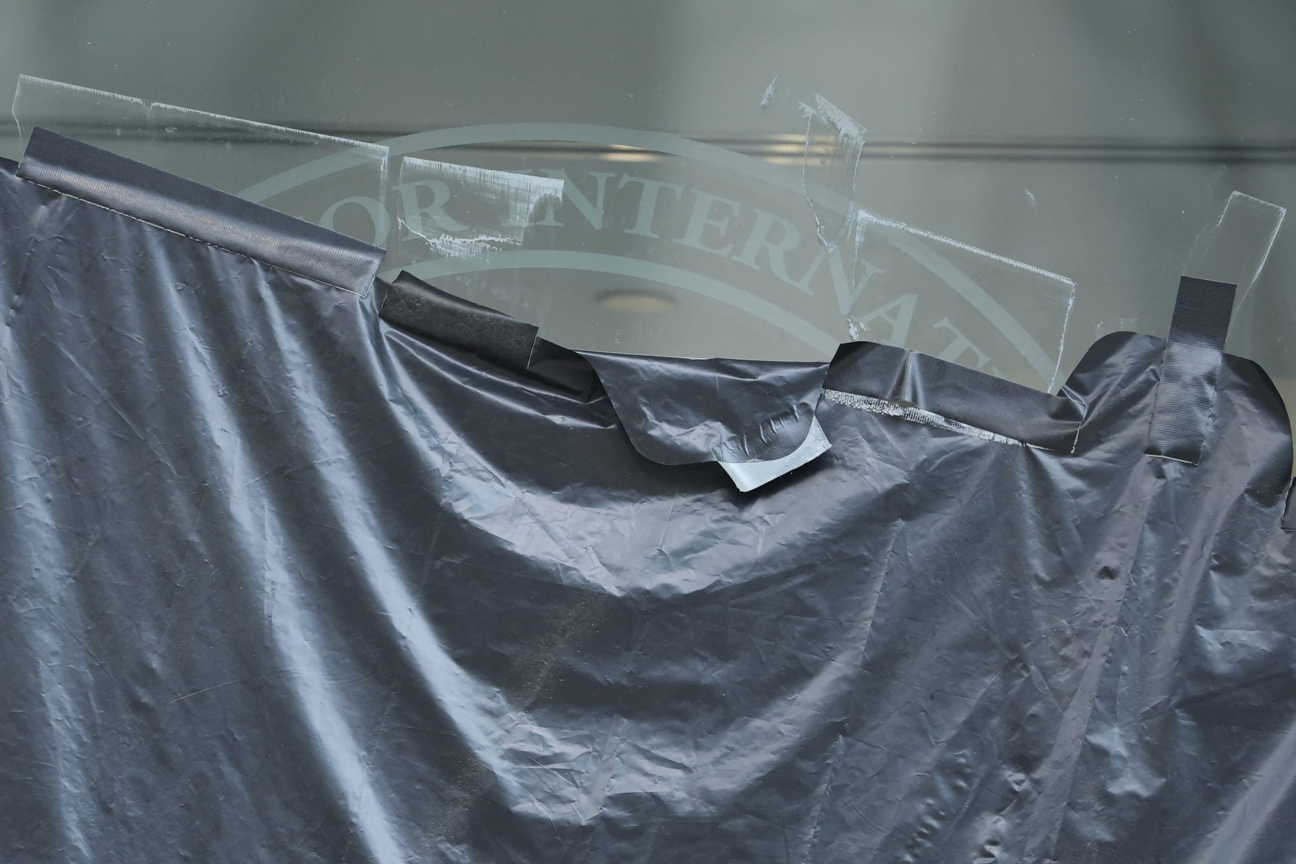 Plastic peels back to reveal the covered logo on the windows of the shuttered offices of the U.S. Agency for International Development, in Washington, DC, on July 22, 2025.