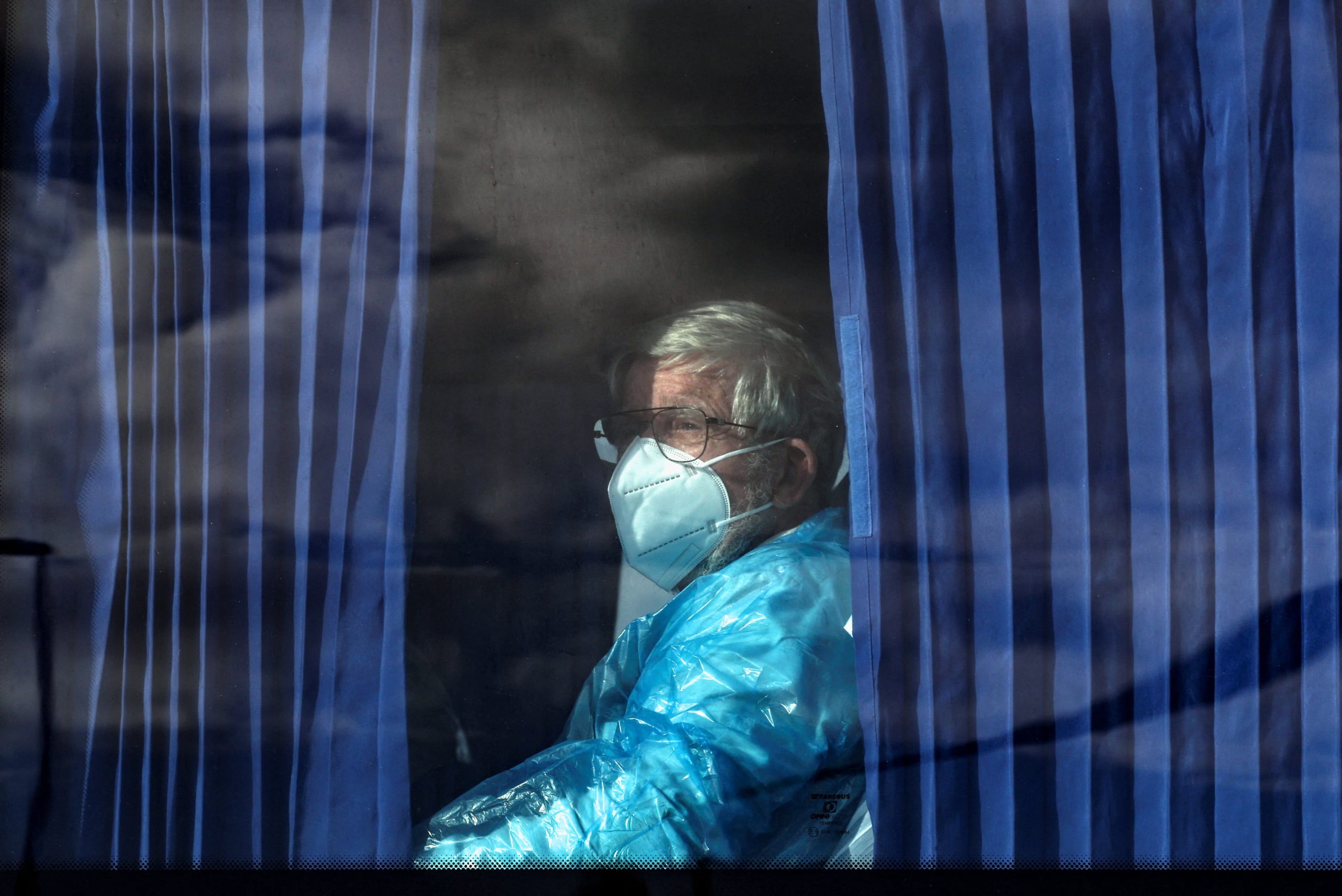 A passenger of the cruise ship MV Hondius, affected by a hantavirus outbreak, looks on from inside a bus as it leaves the port of Granadilla de Abona, in Tenerife, Spain, on May 11, 2026.