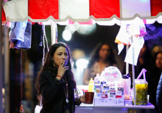 A woman smokes a cigarette next a food stall, before the Mexican government's regulation of the general law for tobacco control, in Monterrey, Mexico, on January 14, 2023.