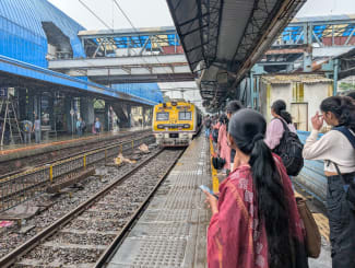 Commuters wait for a train at Goregaon railway station in suburban Mumbai on August 7, 2025.