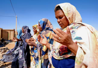 Women pray in front of a house struck by a drone in El-Obeid, North Kordofan State, Sudan, on January 12, 2026.