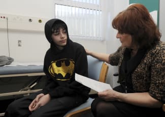School Nurse Carolyn Rees talks to Kieran Elford, aged 13, about the MMR vaccine at the pediatric outpatients department at Morriston Hospital, in Swansea, south Wales, on April 6, 2013.