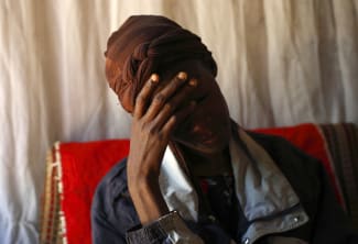 An HIV patient places her hand on her forehead during a visit by a caregiver at her home, in Lusaka, Zambia, on April 17, 2012.
