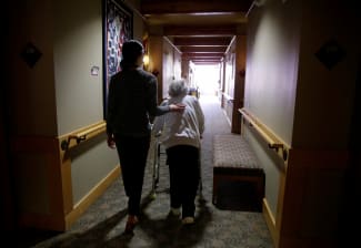 An elderly woman is guided back to her room for a family visit at Nikkei Manor, an assisted living facility, in Seattle, Washington, on March 30, 2021.