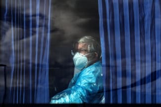 A passenger of the cruise ship MV Hondius, affected by a hantavirus outbreak, looks on from inside a bus as it leaves the port of Granadilla de Abona, in Tenerife, Spain, on May 11, 2026.