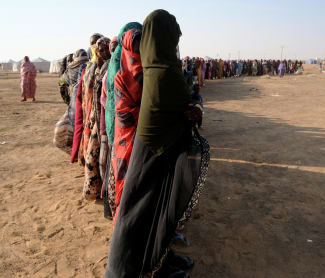 Displaced women stand in a long queue to receive food supplies at a displacement camp, in Al-Dabbah, Sudan, on November 13, 2025.