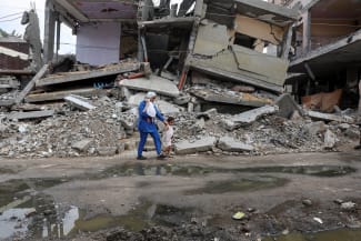 A displaced Palestinian mother, Wafaa Abdelhadi, walks past the rubble of a house destroyed in an Israeli strike as she returns to her shelter with her daughters Lynn and Roueida, after they got vaccinated against polio, in Deir Al-Balah, in the Gaza Strip, on September 1, 2024.