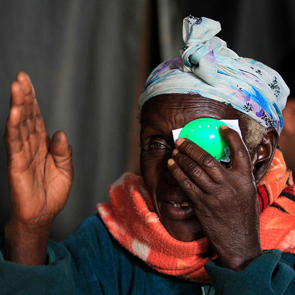 A woman at a clinic in Olenguruone, Kenya on Oct. 29, 2013 undergoes an eye exam, cataract check, and retinal scan with a technology using smartphones that uploads the data to a doctor for analysis. The photo shows a mature woman wearing a bright orange scarf taking an eye test, holding a green patch to her left eye and raising her right hand in front of her face. REUTERS/Noor Khamis 