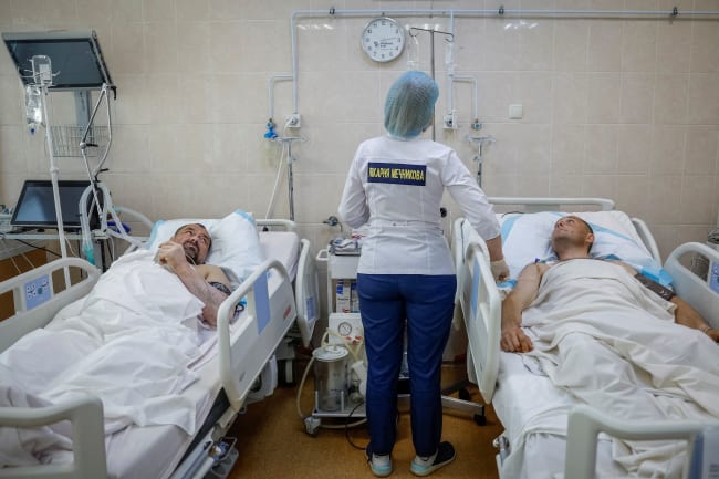 A nurse at the Mechnikov Hospital treats service members Viktor Cherniy, 52, and Vitalii Yunatskyi, 40, who were wounded during fighting against Russian forces, in an intensive care unit, in Dnipro, Ukraine, on May 14, 2025.