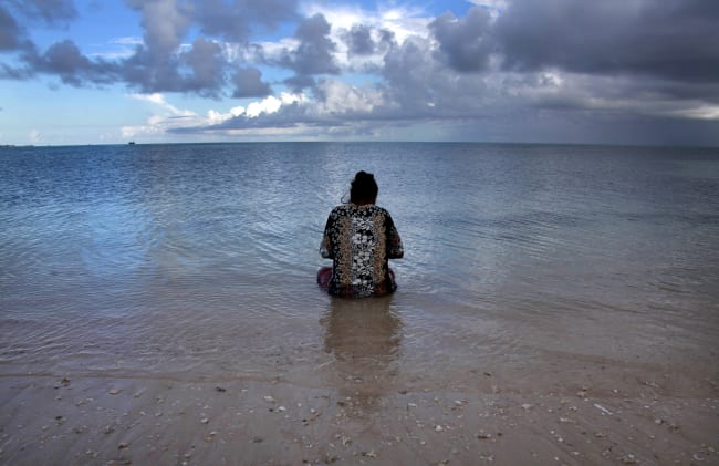 Binata Pinata scales a fish her husband caught, as she sits in the sea just off Bikeman islet, located off South Tarawa, in the central Pacific island nation of Kiribati, on May 25, 2013.