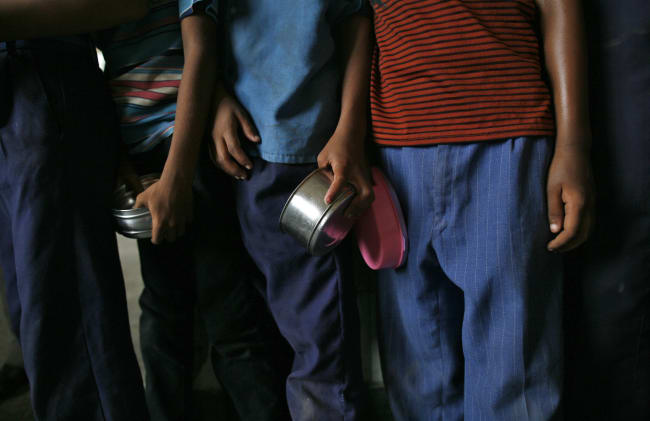 School boys carry their tiffin boxes as they wait to receive their free mid-day meal, distributed by a government-run primary school, in New Delhi, India, on July 19, 2013.